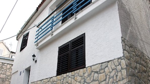 A building with a stone facade, a white upper section, and blue railings on the balcony. - Holiday Home Serov - four bedroom house (Tisno)