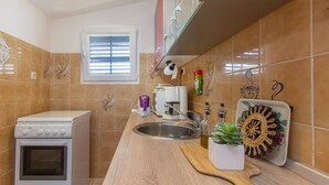 A kitchen with a built-in oven, a sink, and a window with blinds. - Apartments Alaga - B4+2 (Tribunj)