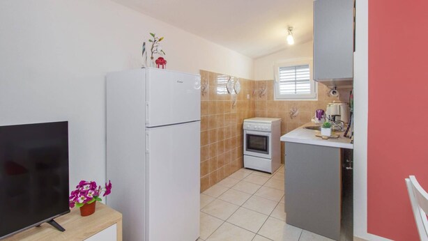 A compact kitchen with a refrigerator, oven, and a small countertop with a sink.