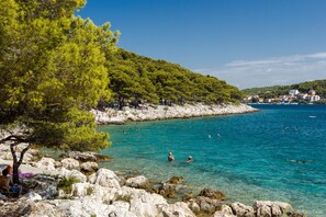 A coastal area with clear turquoise water, rocky shorelines, and a backdrop of lush green hills. - Apartments Kaina Tisno - sea view (yellow) (Tisno)