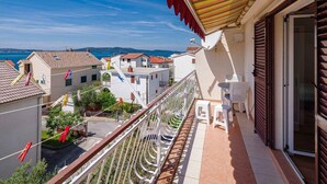 A balcony with a view of the sea, white chairs, and a striped awning. - Apartments Maretic Brodarica A2 (Šibenik-Brodarica)