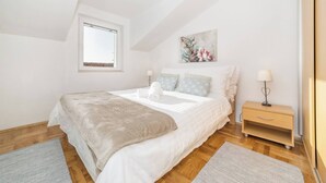 Une chambre à coucher avec un grand lit, une table de chevet, une fenêtre et un tableau au mur.
