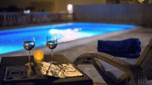 Une table placée au bord de la piscine, avec deux verres de vin, une bougie et un menu.