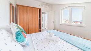 A bedroom with a bed, a wardrobe, a window with a view, and an air conditioning unit. - Apartments Nikol Vodice - sea view A5 (Vodice)