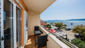 Ein Balkon mit Meerblick, einem Tisch, Stühlen und einer Glastür.