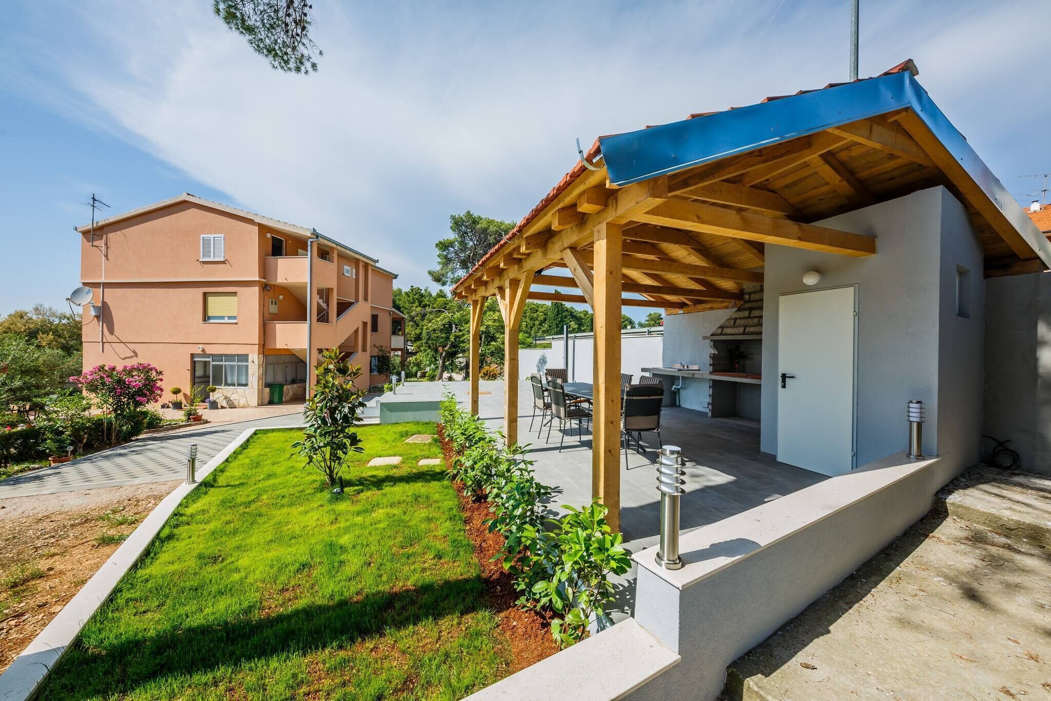 A residential building with a covered patio area, a well-maintained lawn, and a neighboring building.