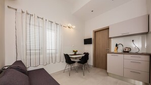 A modern room with a bed, a dining table with chairs, a kitchen area, and a TV mounted on the wall. - Beachfront One Bedroom Apartment Savin (Šibenik-Brodarica)