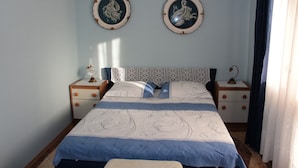 Un dormitorio con una cama, dos mesitas de noche, un cabecero y dos placas decorativas colgadas en la pared.