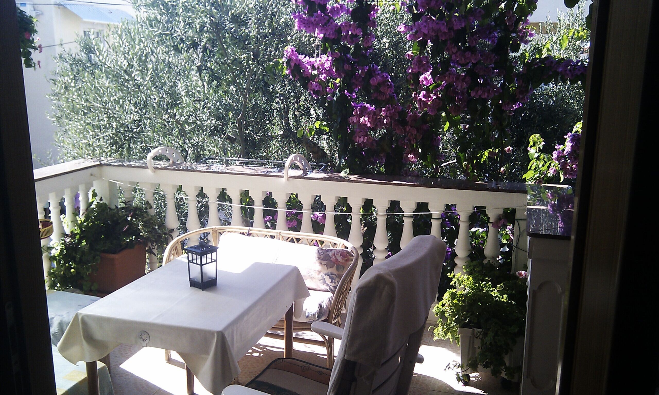 Ein Balkon mit Tisch, Stühlen, einer Brüstung und Blumentöpfen.