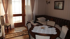 Una sala de estar acogedora con una mesa de comedor de madera, un sofá y una alfombra estampada.