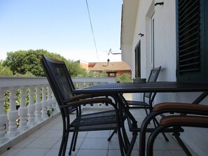Enjoy a peaceful outdoor space with a table and chairs, overlooking the surrounding buildings and lush greenery.