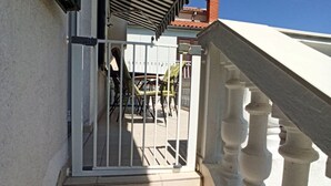 A staircase leading to a balcony with a metal gate, a tiled floor, and a white balustrade.