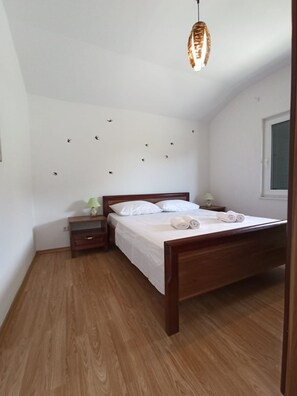 Une chambre à coucher avec un lit en bois, une table de chevet, une lampe et un luminaire au plafond.