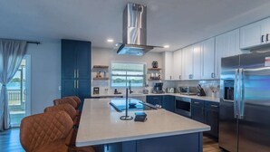 Une cuisine moderne dotée d’un îlot central, d’appareils électroménagers en acier inoxydable et de meubles de couleur bleue.