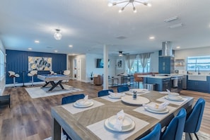 A modern dining area with a wooden table set for four, surrounded by blue chairs.