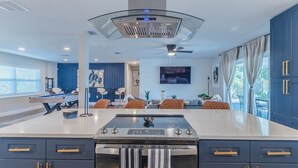 Une cuisine moderne dotée d’un îlot central, de meubles de couleur bleu foncé et d’un ventilateur de plafond.
