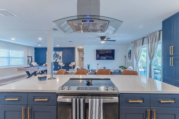 A modern kitchen with a central island, dark blue cabinets, and a ceiling fan.