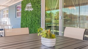 Une table avec un pot de fleurs, un mur agrémenté d’un jardin vertical, et une pancarte indiquant « Résidence de vacances au bord du lac ».