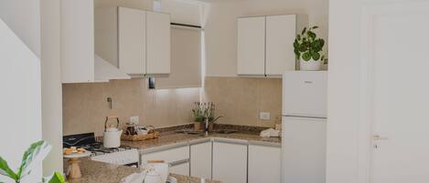 A modern kitchen with white cabinets, a granite countertop, and a built-in stove.