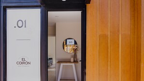 A hotel entrance with a sign reading "EL COIRÓN Apart Patagónico" and a small table with a vase and a sign that says "SO."
