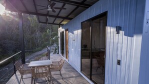 A covered patio with a table and chairs, large sliding glass doors, and a view of the surrounding forest. - top design, Pool, View, ACs, Terrasse with Ventilator, gutes Internet, Parkplätze (Los Pargos)