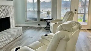 Een moderne woonkamer met een groot raam, een open haard en een relax fauteuil.