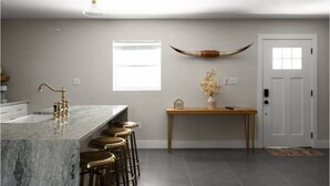 Una cocina con una isla de mármol, taburetes de bar, una mesa de madera y una decoración con forma de cuerno de toro.