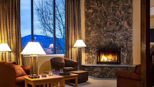 Un salón acogedor con chimenea de piedra, dos lámparas, un sofá y una mesa.