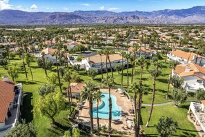 A residential area with houses, a swimming pool, and mountains in the background. - Cozy Desert Escape Available! 2BR Condo Golf & Pool (Palm Desert)