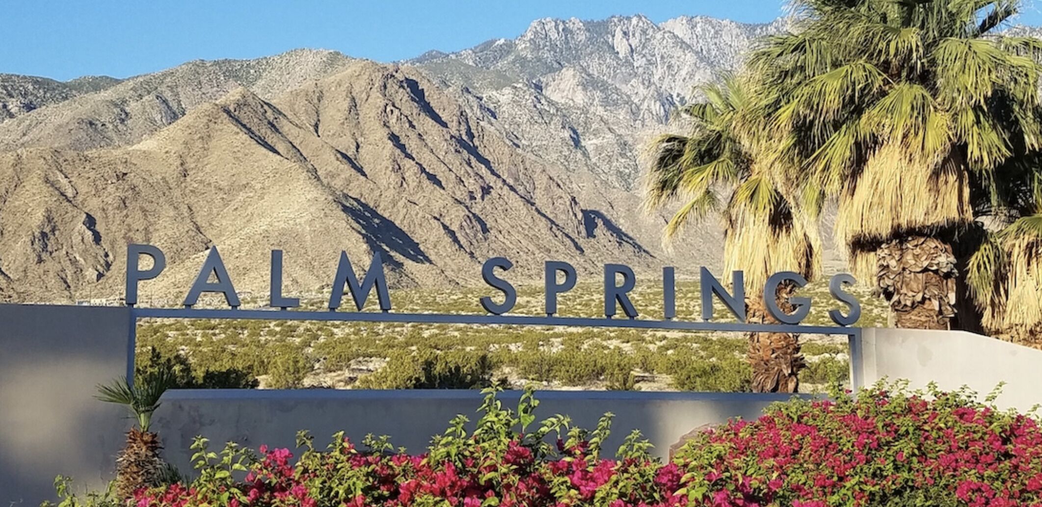 Un panneau indiquant l’entrée de Palm Springs, avec une chaîne de montagnes en arrière-plan.