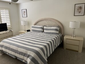 A neatly arranged bedroom with a bed, bedside tables, a lamp, and a TV. - Cozy Desert Escape Available! 2BR Condo Golf & Pool (Palm Desert)