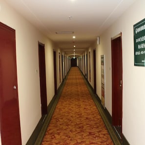 A hotel corridor with doors on both sides, a carpeted floor, and a sign on the right wall. - Greentree Inn Jiangsu Nanjing Olympic Sports Center Express Hotel Nanjing (Nanjing)