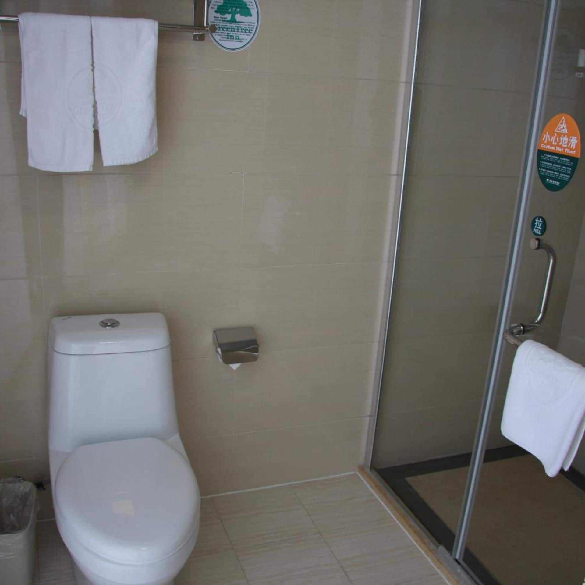A bathroom with a toilet, a hand dryer, and a glass shower enclosure.
