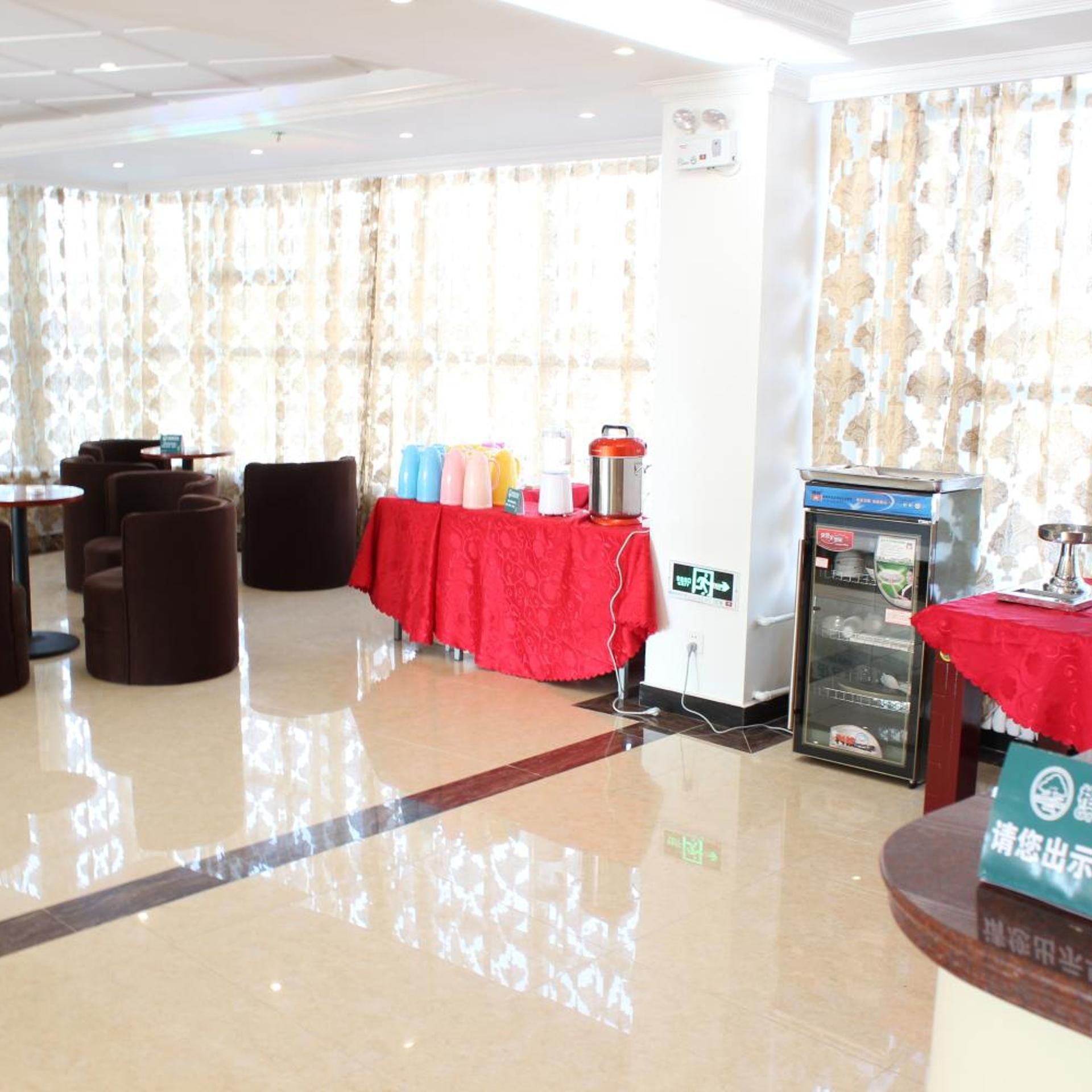 Un vestíbulo de hotel con una mesa roja, sillas, un refrigerador y una máquina expendedora.