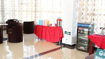 Un vestíbulo de hotel con una mesa roja, sillas, un refrigerador y una máquina expendedora.