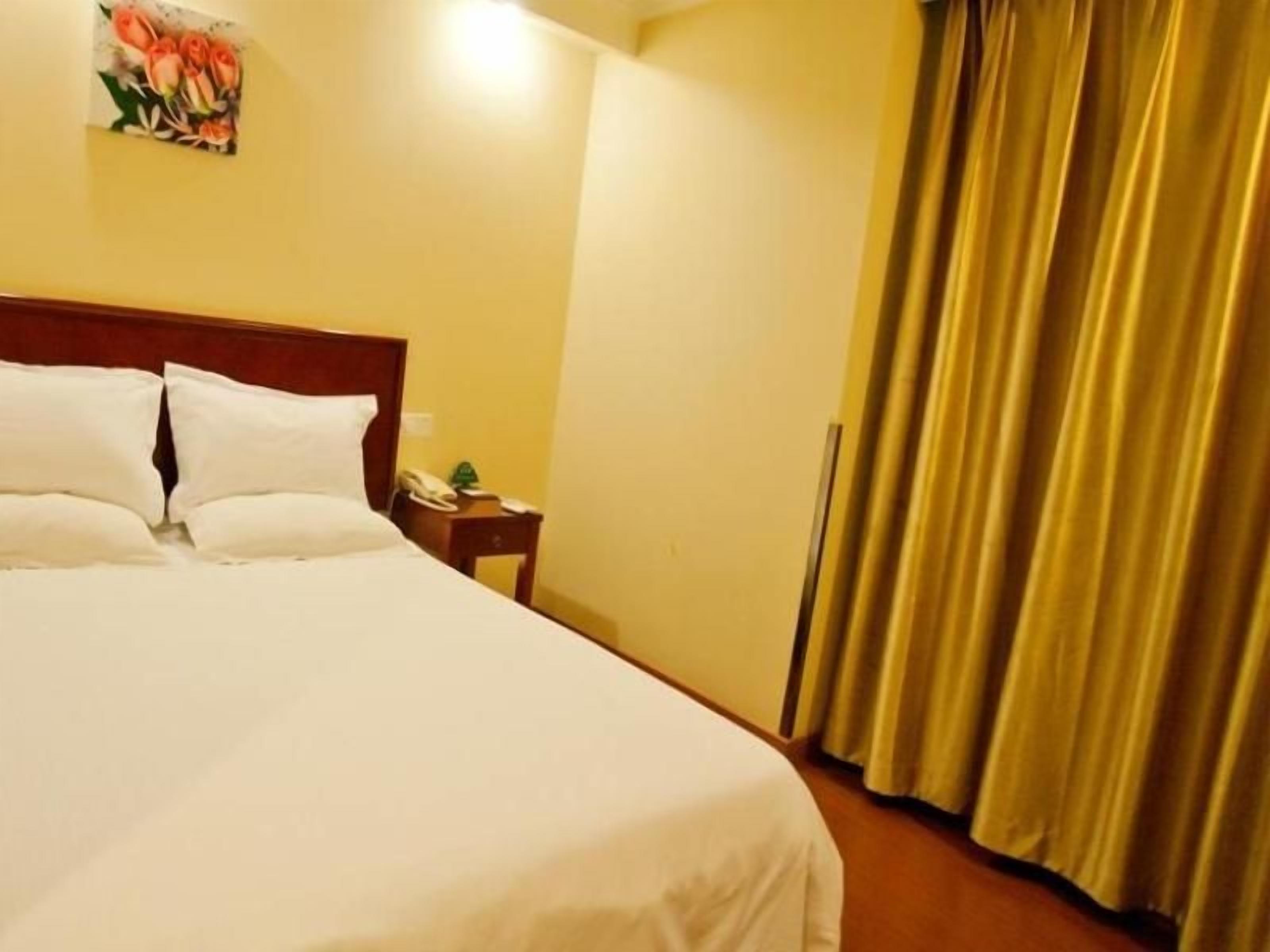 Ein Hotelzimmer mit einem großen Bett, einem Nachttisch mit Telefon und einem Vorhang.