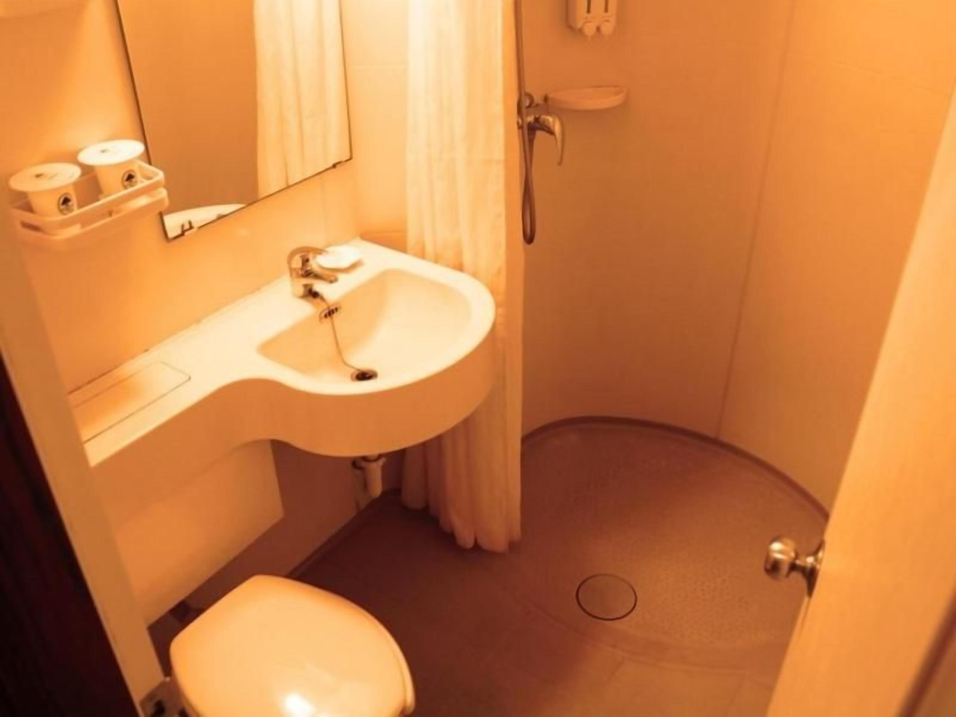 A small bathroom with a sink, toilet, and shower.