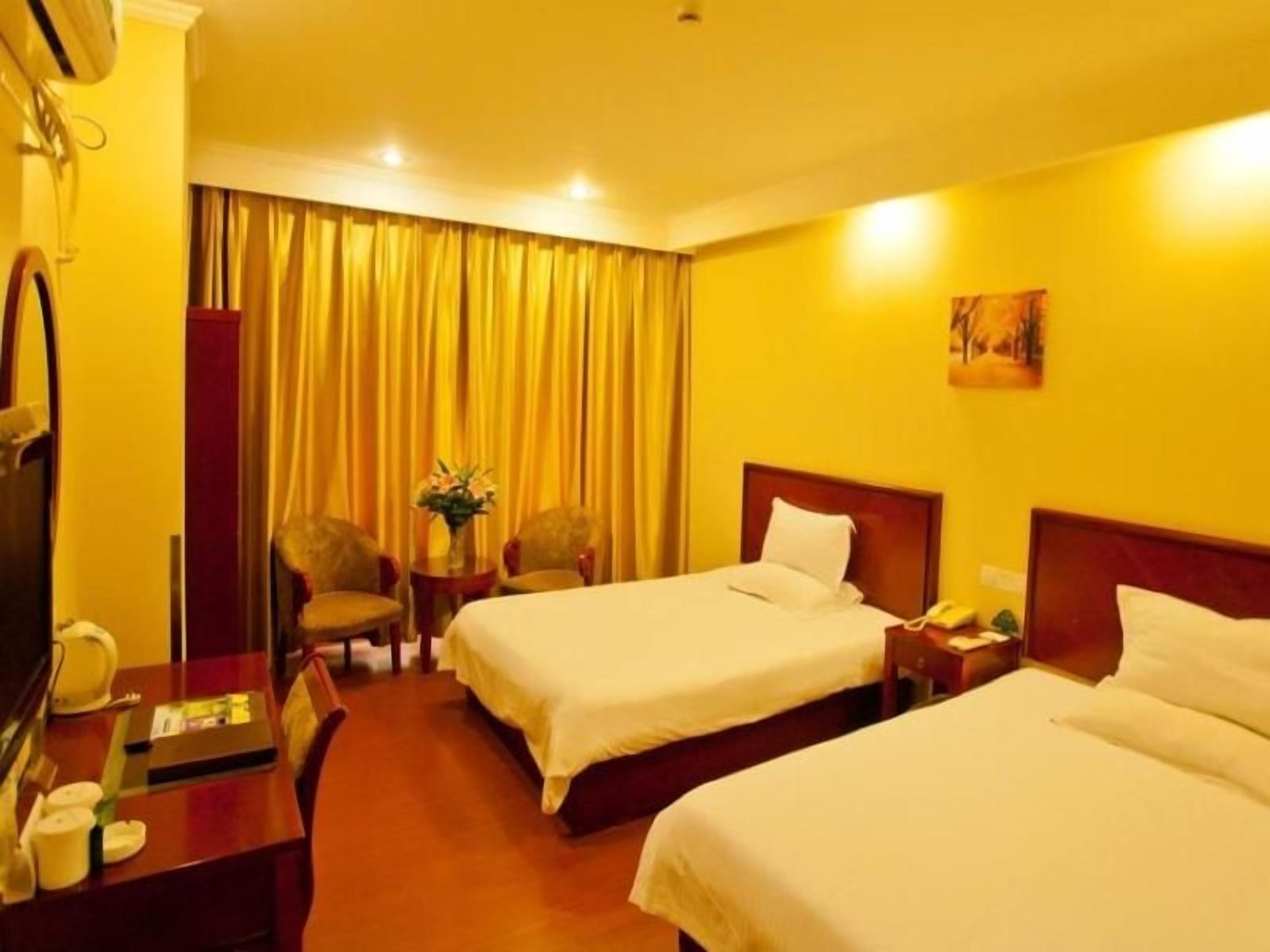 Quarto de hotel com duas camas, uma mesa de trabalho com telefone e uma cadeira.
