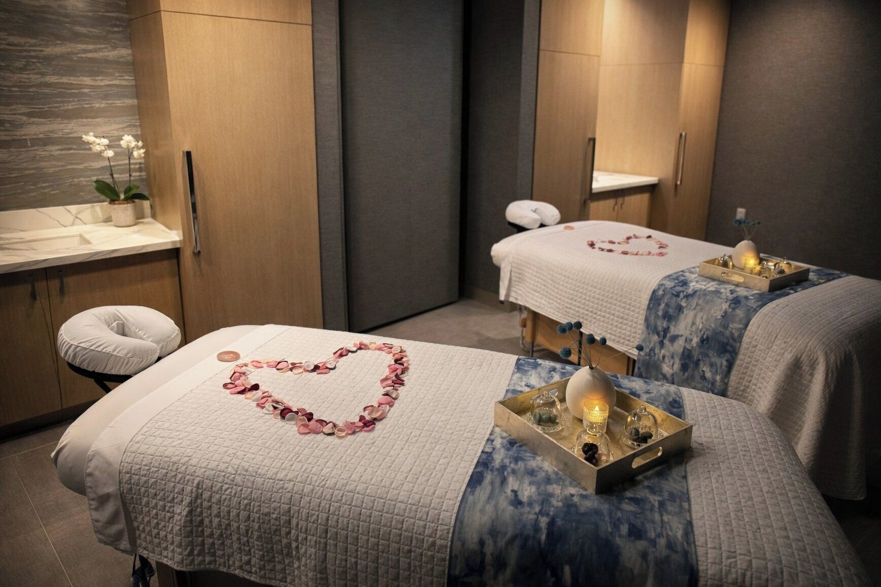 A spa room with two beds, each with a heart-shaped decoration and a tray with candles.