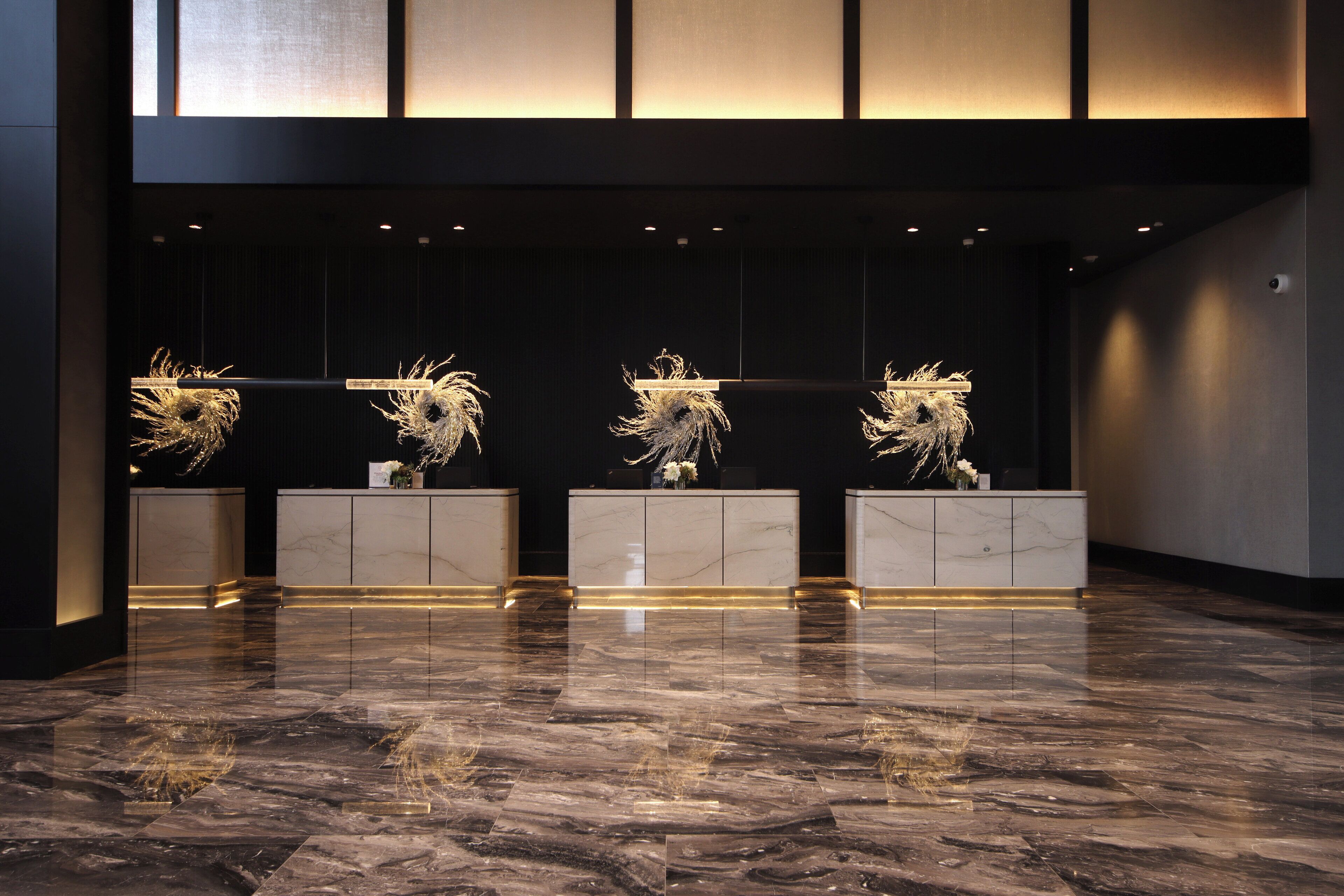 A lobby with a marble floor, a reception desk, and three decorative sculptures.