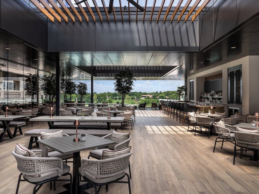 A spacious outdoor dining area with modern furniture and a view of the landscape.