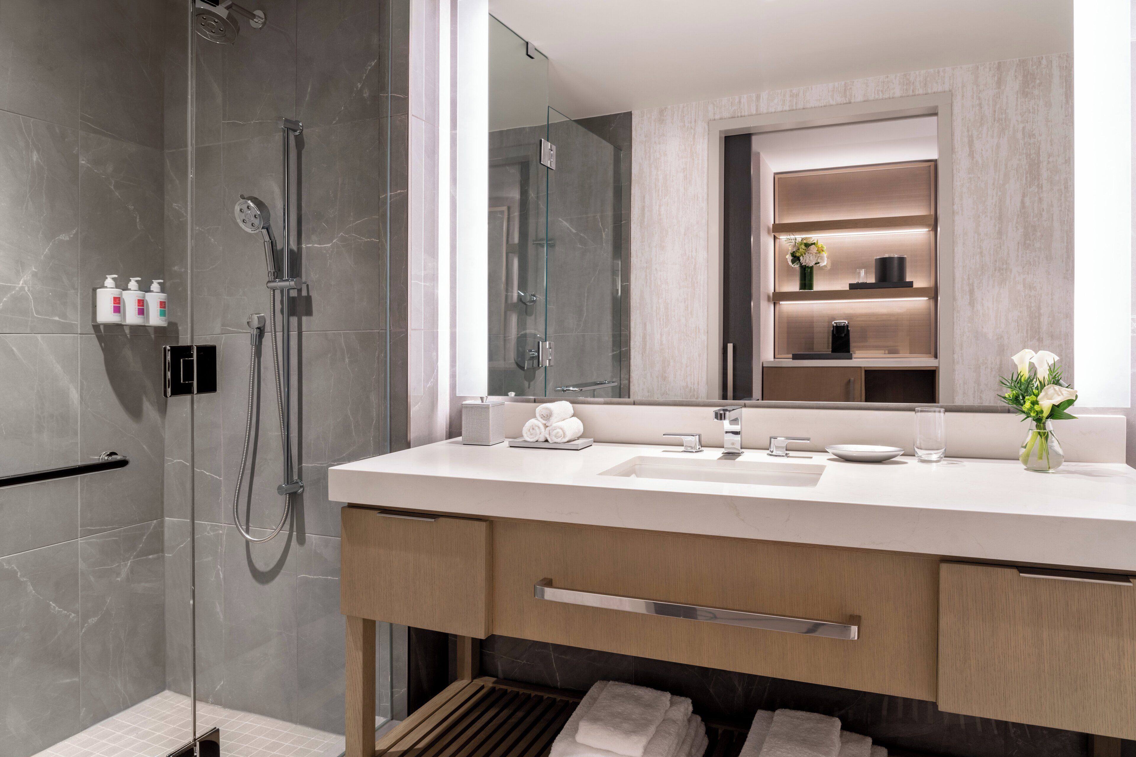 A modern bathroom with a glass-enclosed shower, a white sink, and a mirror above it.