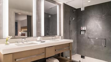 Un baño moderno con un espejo grande, dos lavamanos, una ducha y un perchero para toallas.