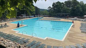 Une piscine rectangulaire dotée de plusieurs couloirs, entourée de chaises longues et d’une zone sablonneuse.