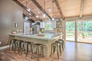 A spacious kitchen with a large island, bar stools, and a view of the outdoors.