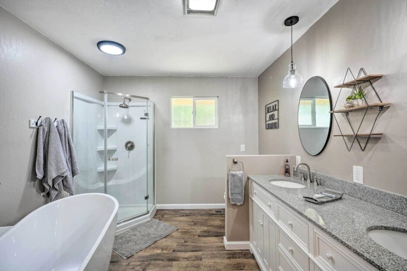 A modern bathroom with a glass shower, a freestanding bathtub, and a vanity with a large mirror.
