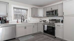 Una cocina moderna con armarios blancos, electrodomésticos de acero inoxidable, microondas integrado y lavavajillas.