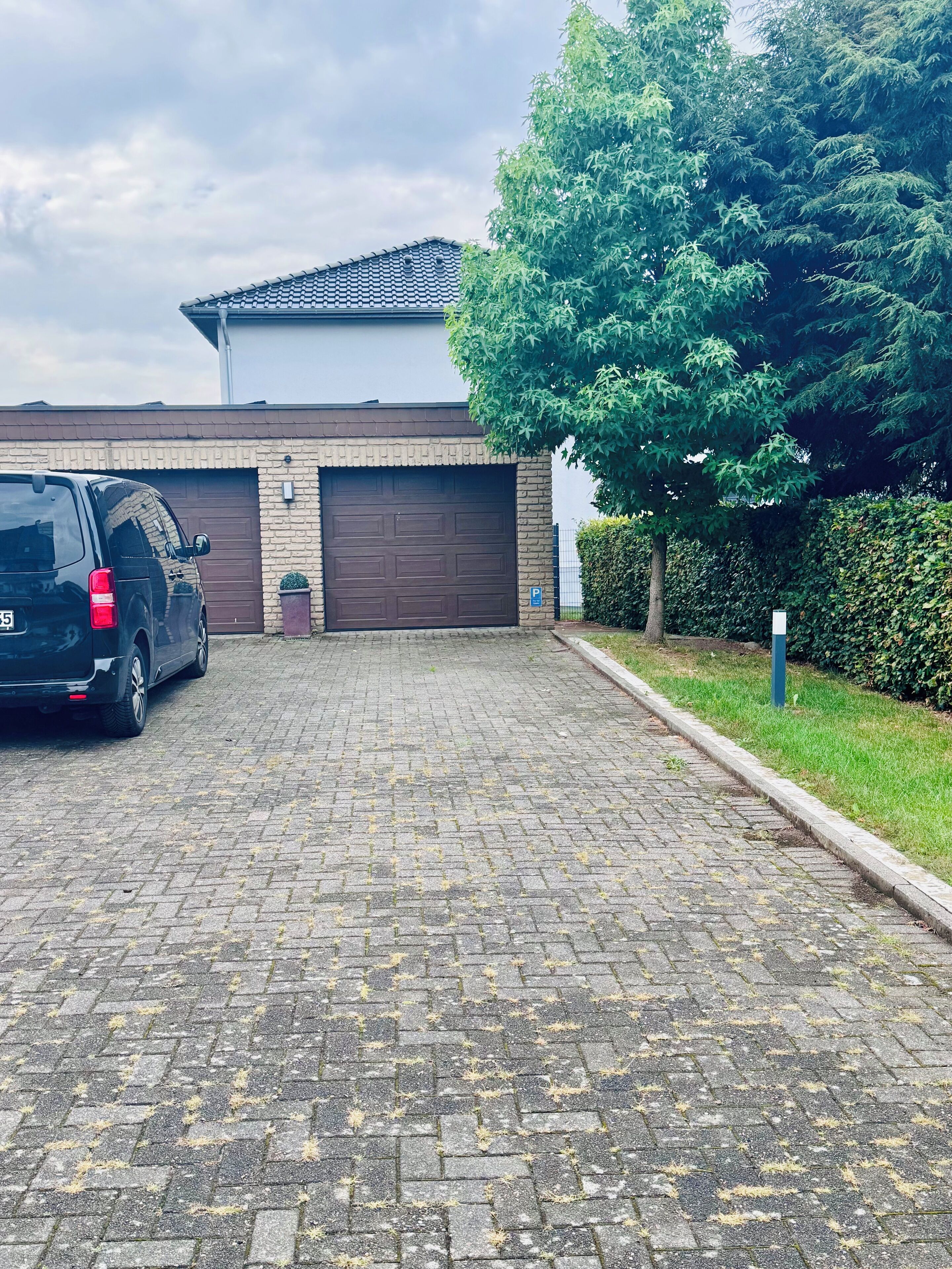 A paved driveway leading to a garage with a parked SUV.