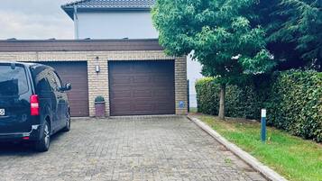 A paved driveway leading to a garage with a parked SUV.