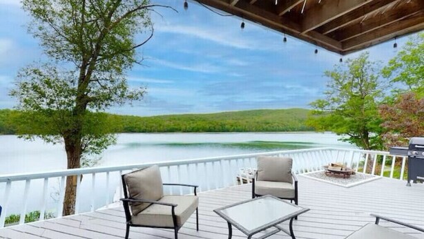 Une terrasse dotée de mobilier d’extérieur, d’un barbecue et offrant une vue sur un lac.